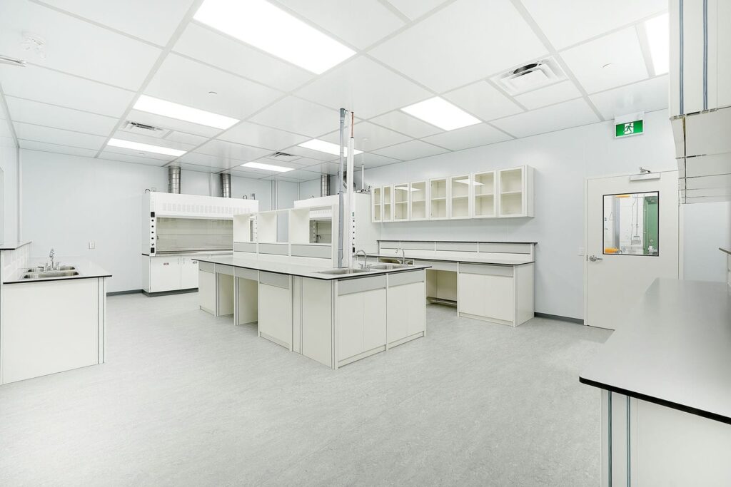 Cleanroom laboratory with chemical fume hoods, integrated sinks, modular casework, and sealed wall and ceiling systems.