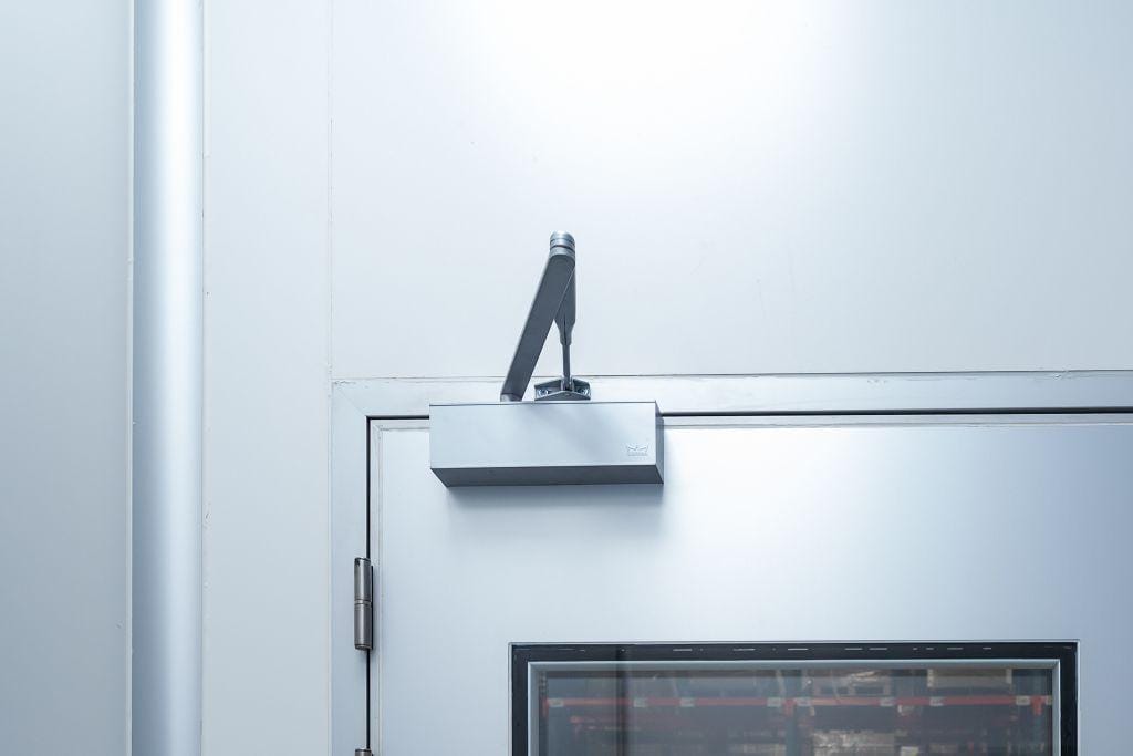 Cleanroom door closer arm and hinge, hardware that controls door closure and helps stabilize pressure cascades