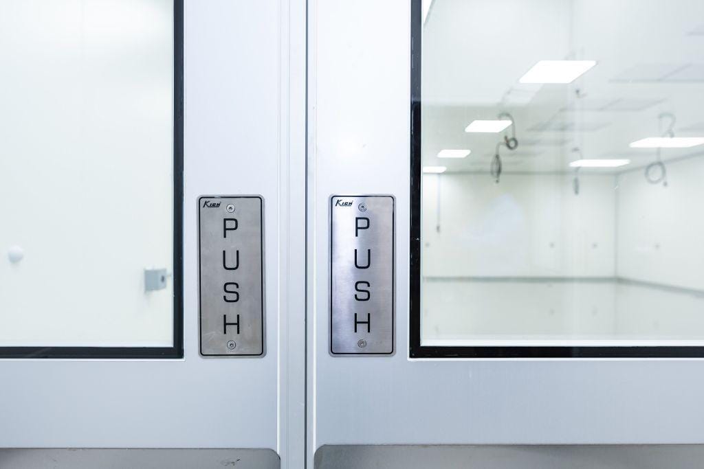 Stainless push plates on cleanroom doors, reflecting operator door use behind common pressure mistakes