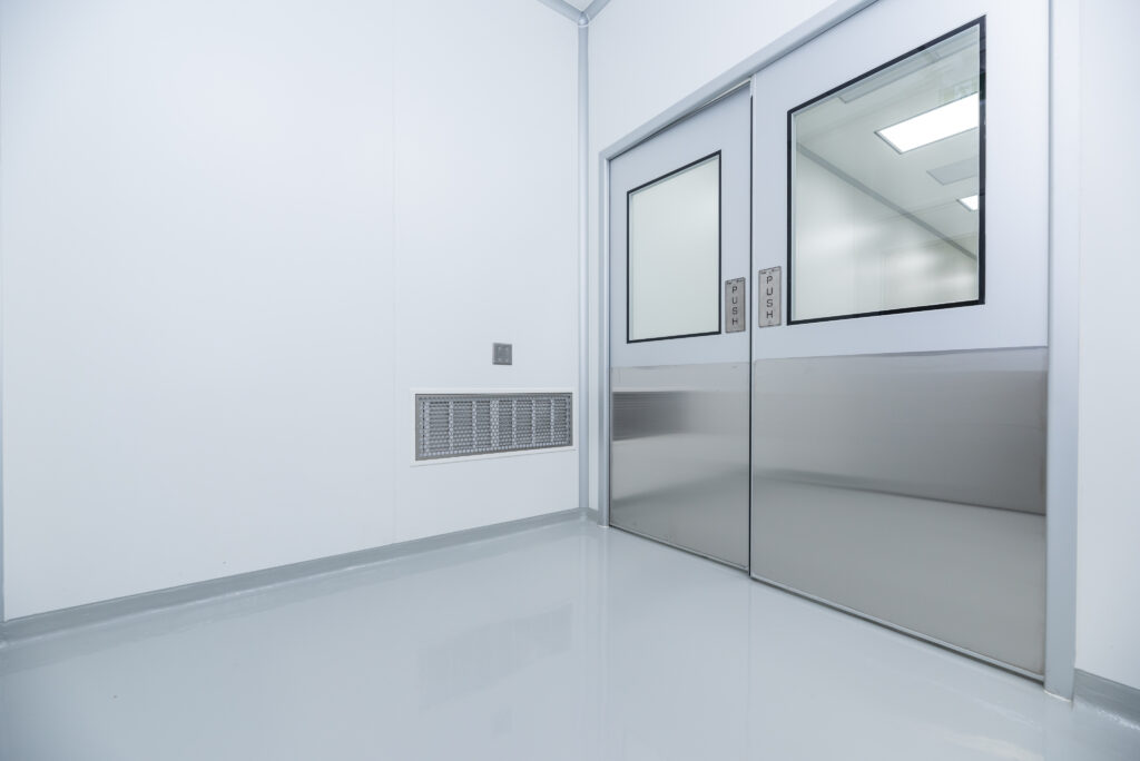 Stainless steel sliding cleanroom doors with double-glazed flush vision panels.